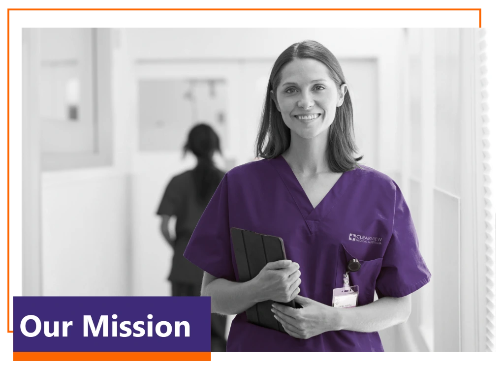 Healthcare professional in purple scrubs holding a tablet in a hallway, with another person in scrubs walking away in the background. Text in the corner reads “Our Mission.”